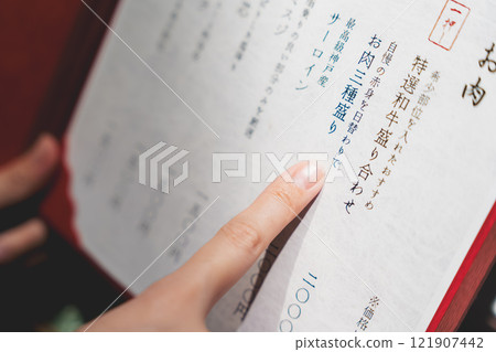 A female customer looks at the menu and makes a selection [Photo courtesy of Seafood Izakaya Gyoruko] 121907442