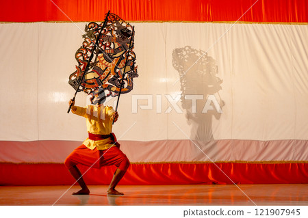 Asian young man stand with perform grand shadow play in front of his team stay behide in the shadow of other charactor craft. 121907945