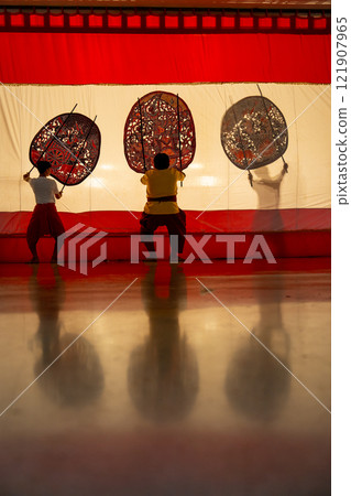 Vertical image of three player men stand with perform grand shadow play with two stay in front of white screen with reflection on the floor. 121907965