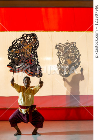 Asian senior man stand with perform grand shadow play in front of his team stay behide in the shadow of other charactor craft. Asian senior man stand with perform grand shadow play in front of his team stay behide in the shadow of other charactor craft. 121907966