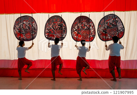 Four player men stand with perform grand shadow play in front of white screen with lift leg as performance of the show. Four player men stand with perform grand shadow play in front of white screen with lift leg as performance of the show. 121907995