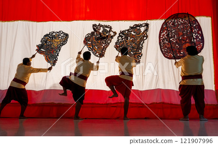 Four player men stand with perform grand shadow play in front of white screen with some of them lift leg as performance of the show. 121907996