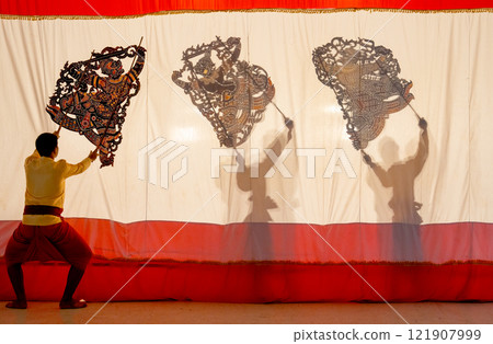 The player men stand with perform grand shadow play with one stand in front of white screen and the other two stay behide the screen. The player men stand with perform grand shadow play with one stand in front of white screen and the other two stay behide the screen. 121907999