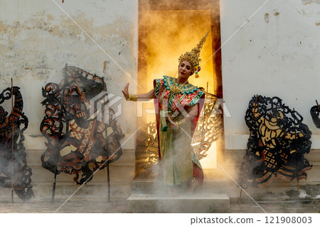 One woman with Khon mask charactor as angel stand and performance action in front of door frame of old building also some crafts in front of old building and warm light in the back of room. 121908003