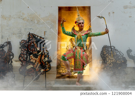 One man with Khon mask charactor as angel stand and performance action in front of door frame of old building also some crafts in front of old building and warm light in the back of room. One man with Khon mask charactor as angel stand and performance action in front of door frame of old building also some crafts in front of old building and warm light in the back of room. 121908004