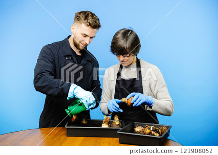 Working couple in a family business of florist store, they plants the flowers on the pot together and enjoy the process Working couple in a family business of florist store, they plants the flowers on the pot together and enjoy the process 121908052