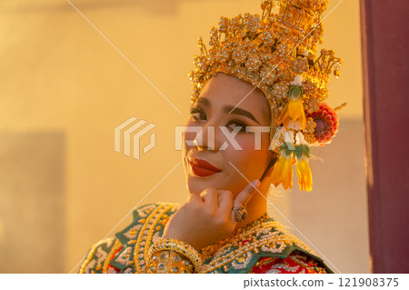 Close up of one woman with Khon Mask costume stand with at camera at window frame with warm light in the back. Close up of one woman with Khon Mask costume stand with at camera at window frame with warm light in the back. 121908375