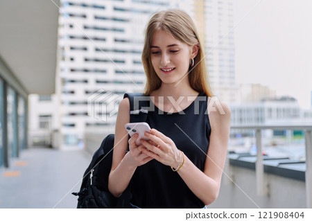 Young female using smartphone, modern city background 121908404