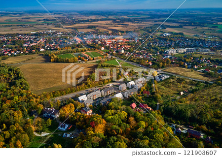 Aerial view of beautiful small town surrounded by fields and forest in autumn season. Bird eye view of village in Poland. Landscape with residential buildings in suburban neighborhood 121908607