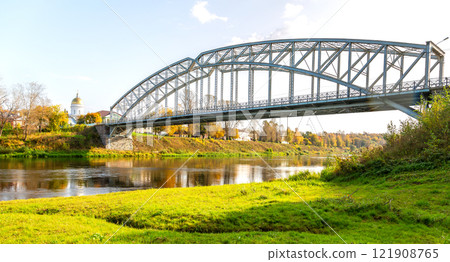 View on the steel arch bridge across the Msta river in summer. Built in 1905. Borovichi, Russia 121908765