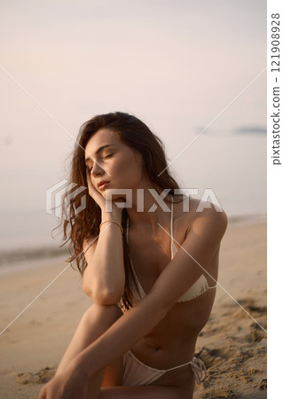 Sitting Beautiful model in sand on the beach. Sexy girl in Bikini Sitting Beautiful model in sand on the beach. Sexy girl in Bikini 121908928
