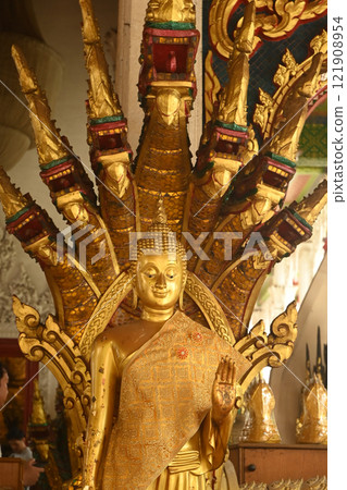 Golden standing Buddha statue and there is a serpent covering the back. decorated front of Buddhist Thai Church at Wat Naga Prok temple. Located at Bangkok capital city in Thailand. Golden standing Buddha statue and there is a serpent covering the back. decorated front of Buddhist Thai Church at Wat Naga Prok temple. Located at Bangkok capital city in Thailand. 121908954