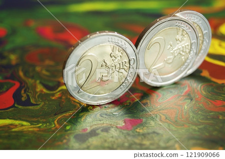 Shiny new 2 euro coins on a mottled abstract surface. 121909066