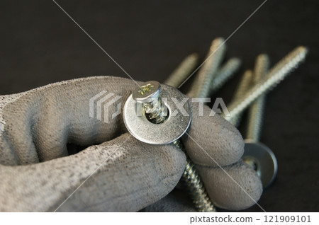 New mounting screw with steel washers in the hand of the assembler. New mounting screw with steel washers in the hand of the assembler. 121909101