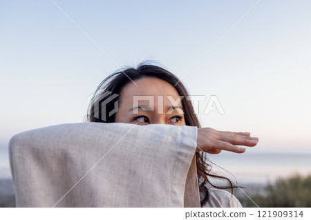 Young attractive Asian with long wavy hair outdoors. A charming Korean woman 121909314