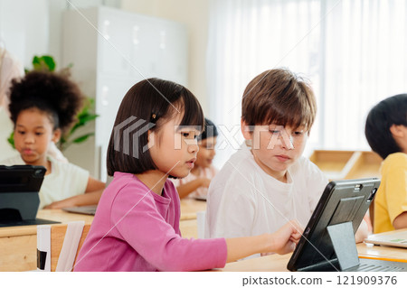 International Students Collaborate on Tablet: Diverse Elementary Classroom Scene Showcases Digital Learning and Multicultural Education in Action 121909376