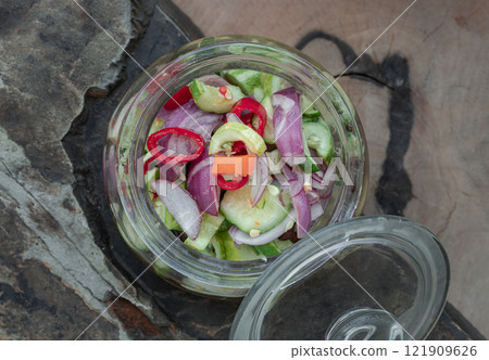 Top view of Homemade thai cucumber slices, chili slices and shallots relish slices and vinegar in a glass jar. Top view of Homemade thai cucumber slices, chili slices and shallots relish slices and vinegar in a glass jar. 121909626
