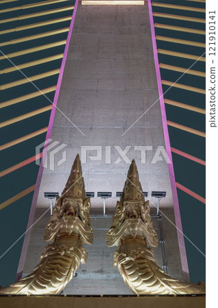 Two golden yellow Naga sculptures on concrete pillars of Thotsamarachan Bridge. 121910141