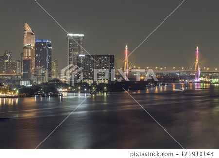 Nightscape city view with bright glowing lighting of Skyscrapers and Bhumibol bridge with Chao phraya river in the foreground. 121910143