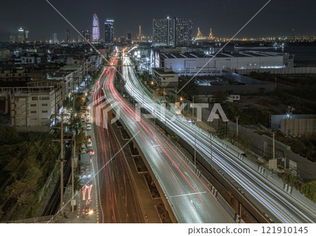 Nightscape view with bright glowing light trails of many cars on the road of Bangkok with Skyscrapers in the background. 121910145