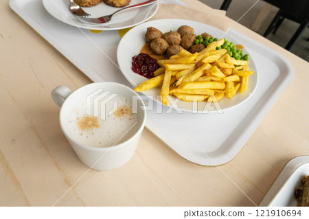 Meatballs with french fries, green peas, bechamel sauce and cranberry jam, meat balls on white plate Meatballs with french fries, green peas, bechamel sauce and cranberry jam, meat balls on white plate 121910694
