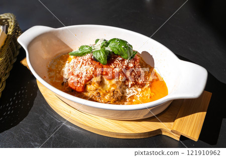 Lasagna portion, oven baked lasagne, pasta layers with cheese, minced meat, tomato in sunny summer day 121910962