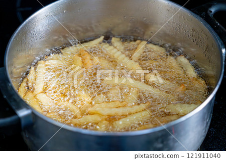 Potatoes in boiling oil, homemade french fries, deep fried potato cooking in metal fryer pot, fat fast food Potatoes in boiling oil, homemade french fries, deep fried potato cooking in metal fryer pot, fat fast food 121911040