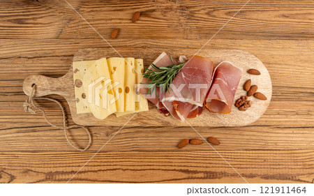 Cheese plate with prosciutto, jamon cut, parma ham, serrano slices, cured iberico closeup, cheese board 121911464
