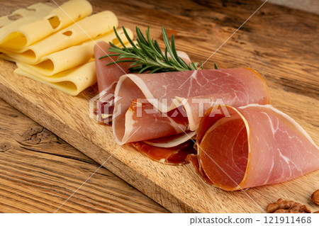 Cheese plate with prosciutto, jamon cut, parma ham, serrano slices, cured iberico closeup, cheese board 121911468