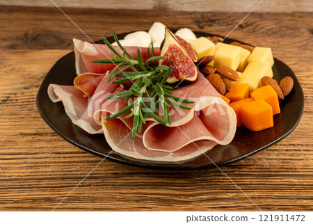 Cheese plate with prosciutto, jamon cut, parma ham, serrano slices, cured iberico closeup, cheese board Cheese plate with prosciutto, jamon cut, parma ham, serrano slices, cured iberico closeup, cheese board 121911472