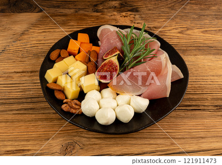 Cheese plate with prosciutto, jamon cut, parma ham, serrano slices, cured iberico closeup, cheese board Cheese plate with prosciutto, jamon cut, parma ham, serrano slices, cured iberico closeup, cheese board 121911473