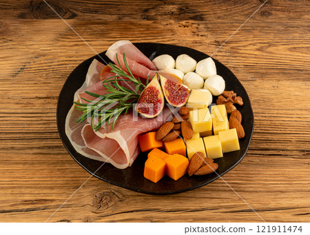 Cheese plate with prosciutto, jamon cut, parma ham, serrano slices, cured iberico closeup, cheese board 121911474