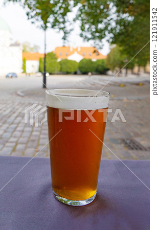 Beer glass, dark cold drink on a old European city blurred background, outdoor tourist cafe, red beer Beer glass, dark cold drink on a old European city blurred background, outdoor tourist cafe, red beer 121911542