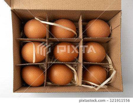 Open egg box with brown eggs. Fresh organic chicken eggs in carton pack container closeup 121911556