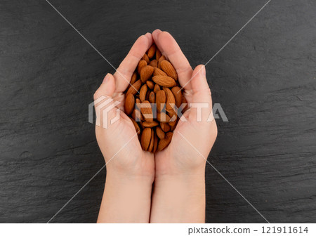 Almonds pile in hands, nut group handful, whole almond seeds, brown scattered fruit kernels, dry raw Almonds pile in hands, nut group handful, whole almond seeds, brown scattered fruit kernels, dry raw 121911614