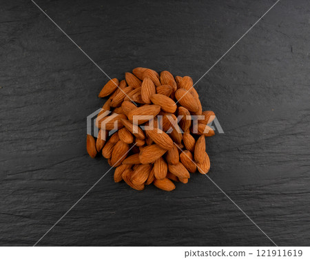 Almonds pile, nut group, whole almond seeds, brown scattered fruit kernels, dry raw nuts on black Almonds pile, nut group, whole almond seeds, brown scattered fruit kernels, dry raw nuts on black 121911619