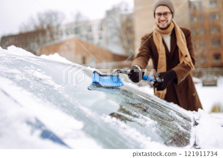 Portrait of smiling man cleaning snow off his car during winter snowfall. Transport, weather concept Portrait of smiling man cleaning snow off his car during winter snowfall. Transport, weather concept 121911734