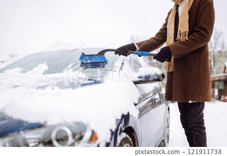 Portrait of smiling man cleaning snow off his car during winter snowfall. Transport, weather concept 121911738