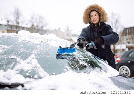 Portrait of man cleaning snow off car during winter snowfall. Weather, people and vehicle concept. 121911822
