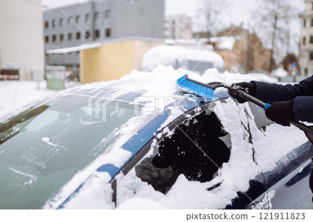 Portrait of man cleaning snow off car during winter snowfall. Weather, people and vehicle concept. Portrait of man cleaning snow off car during winter snowfall. Weather, people and vehicle concept. 121911823