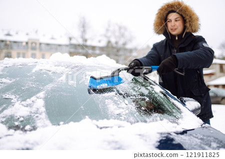 Portrait of man cleaning snow off car during winter snowfall. Weather, people and vehicle concept. 121911825