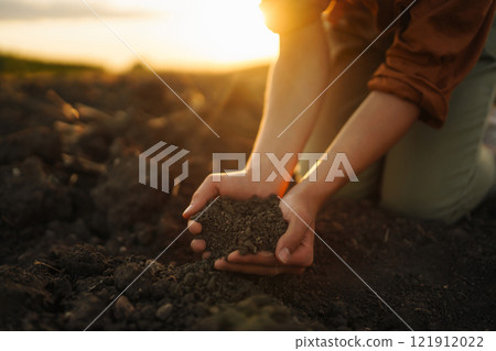 Female hands touching soil on the field. Agriculture, gardening or ecology concept 121912022