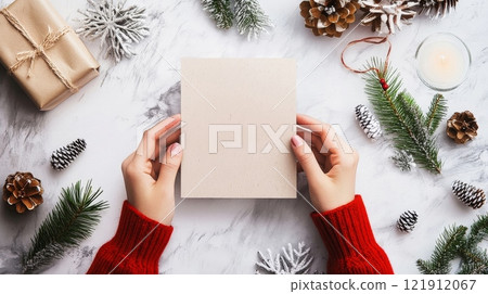 Woman holding christmas card with festive decorations around 121912067