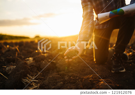 Farm owner checks quality of soil with his hands with tablet and checks fertility before sowing. 121912076