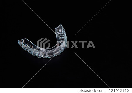 A clear mouth guard is placed on a black tabletop A clear mouth guard is placed on a black tabletop 121912160