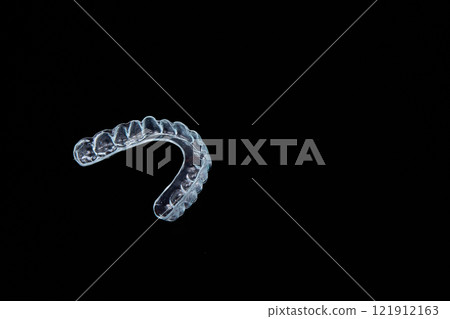 Clear mouth guard on black background with font, art, fashion, metal keywords 121912163
