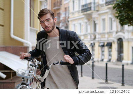 Bike messenger with backpack stands near bicycle and look at camera Bike messenger with backpack stands near bicycle and look at camera 121912402