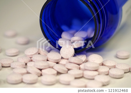White tablets and blue container for nutritional supplements 121912468