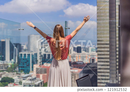Female tourist or businesswoman standing on a skyscraper rooftop with a panoramic view of Mexico City. Travel or international business in Mexico concept 121912532