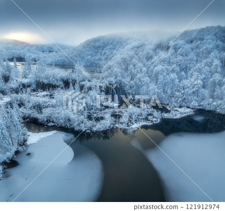 Aerial drone view of amazing waterfall and snowy forest in winter 121912974